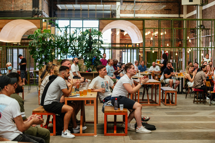 Where to Watch the Rugby World Cup in London: People cheer on a game from a table in a warehouse space