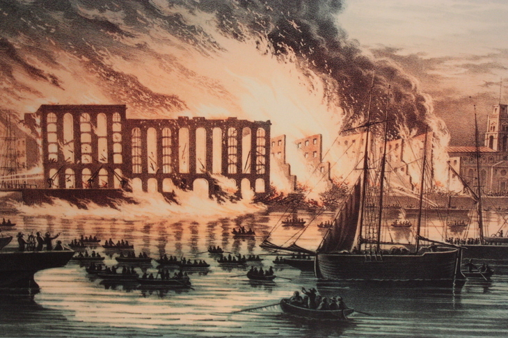 A warehouse on the Thames goes up in flames - with boats in the foreground