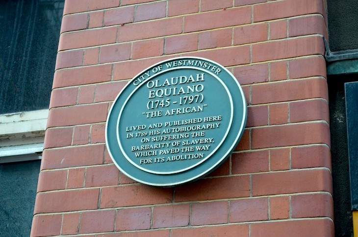 A green plaque to Olaudah Equiano on a red brick wall