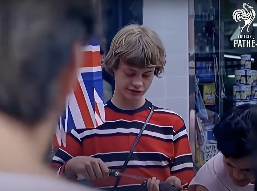 A boy in a red striped shirt with a union flag behind