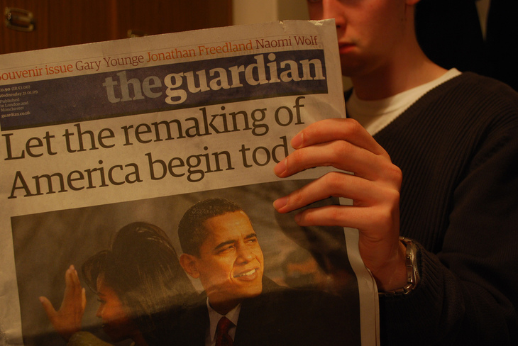 A man reads a copy of the Guardian heralding Obama's new presidency