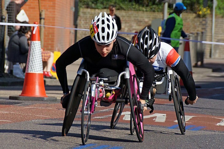 Wheelchair racer Jade Jones taking part in the 2014 London Marathon on  a road on part of the course in the Isle of Dogs, with a second wheelchair racer close behind her