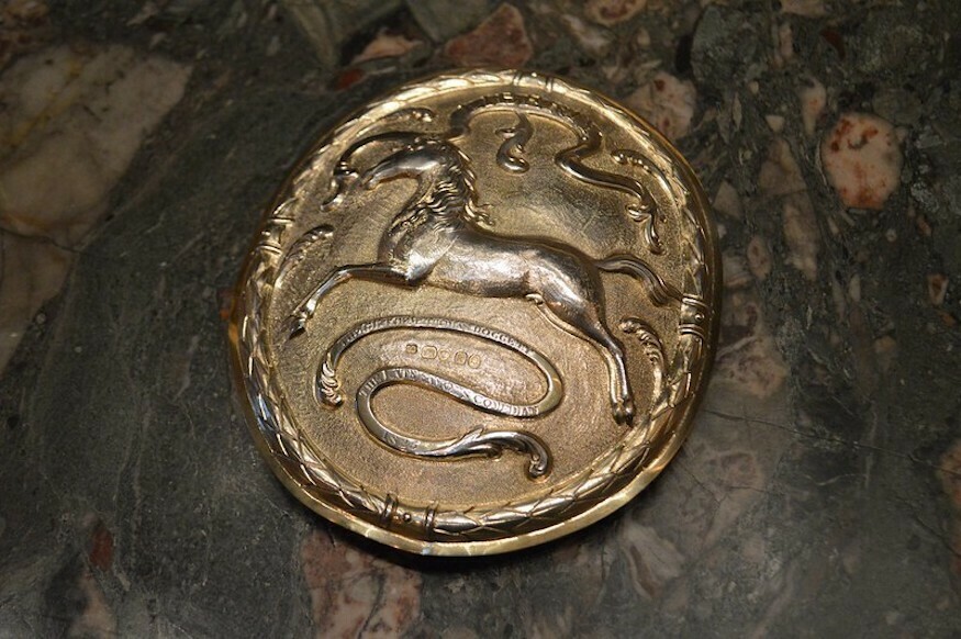 A silver badge with a horse on it