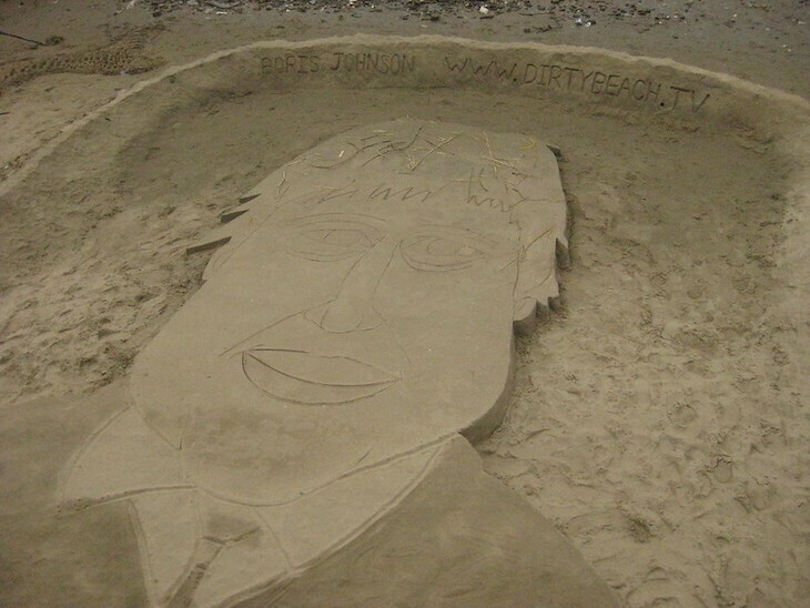 The face of Boris Johnson picked out in sand