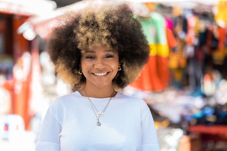 A young woman with afro hair do smiling at the camera