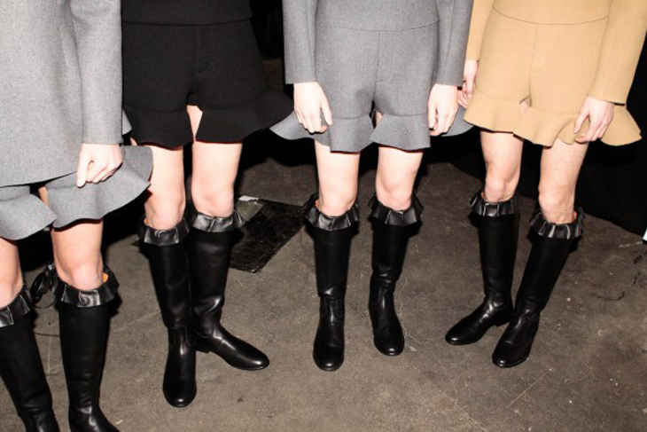 A photograph of four women's lower halves, showing mini skirts and knee-length boots.