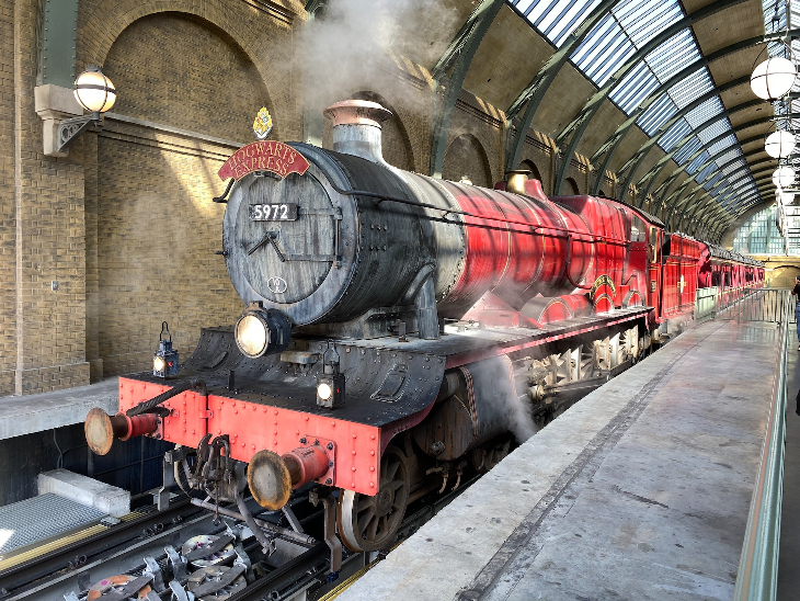 Autumn in London: a replica of the Hogwarts Express steam train parked up alongside a train platform.