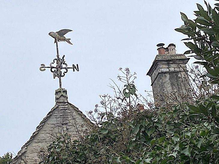 A huge weathervane, topped with a fish on a stone house