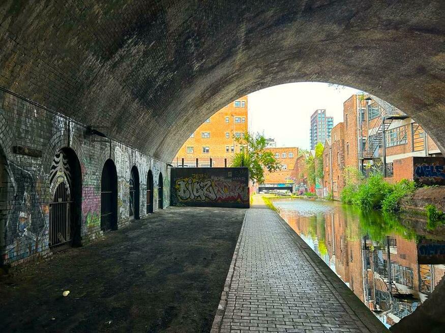 Things to do in Birmingham: A canal arch with vivid brick buildings and trees at the other end