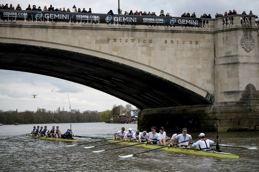 Two rowing teams complete the race under |Chiswick Bridge