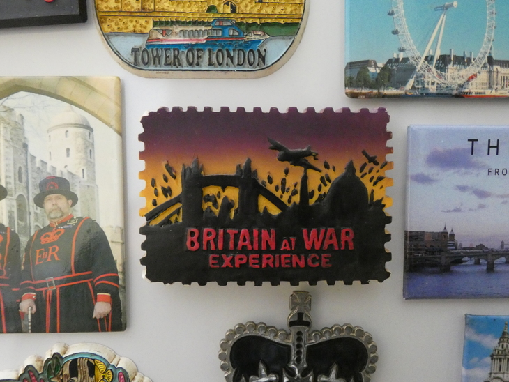 A close up of magnets from London attractions stuck to a fridge. The central one is a rectangle with silhouettes of the London skyline, a bomber plane flying overhead, and 'Britain at War Experience' written in red.
