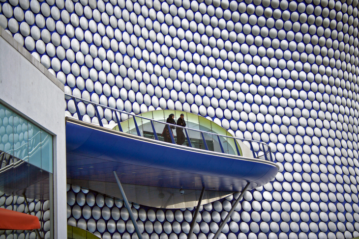 Things to do in Birmingham: Two people perch high up on a balcony set into the curved shape of the Bullring, covered in thousands of Dalek-esque discs