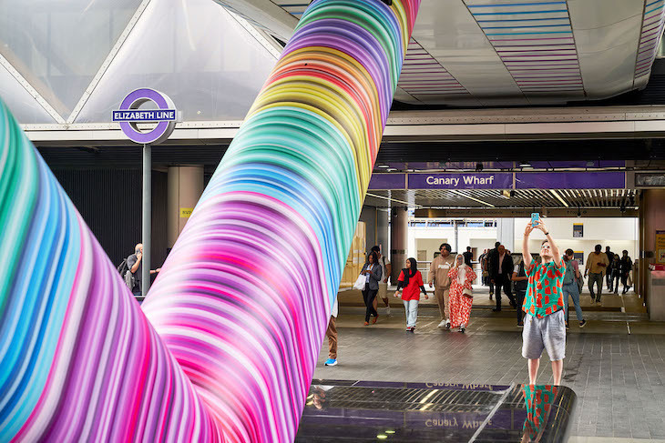 Exit of Canary Wharf Crossrail station, with a colourful V-shaped strut in foreground