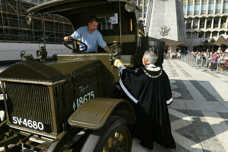 An old army truck being blessed by an alderman in a gown