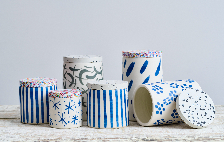 A display of five cylinder-shaped ceramic pots, decorated in different blue and white patterns.