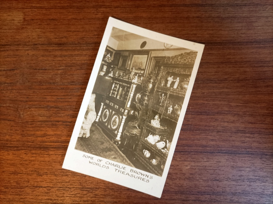 A black and white postcard showing part of the pub stuffed with treasures