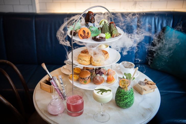 An afternoon tea surrounded by theatrical smoke, with dinosaur themed food and decorations.