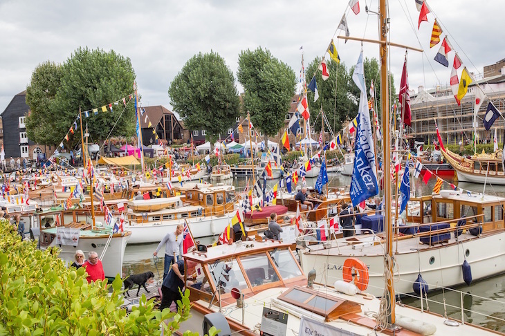 Several Dunkirk Little Ships moored up together at St Katharine Docks, many decked out with bunting and flags