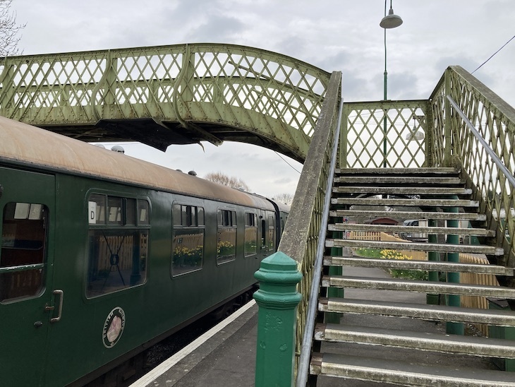 A green footbridge spanning the tracks 