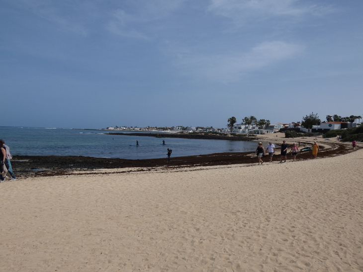 Corralejo in Fuerteventura: people strolling along a curved, sandy beach in Corralejo