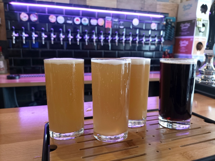 Brewery taprooms in London: Four half pints of beer on the bar, with lots of taps in the background.