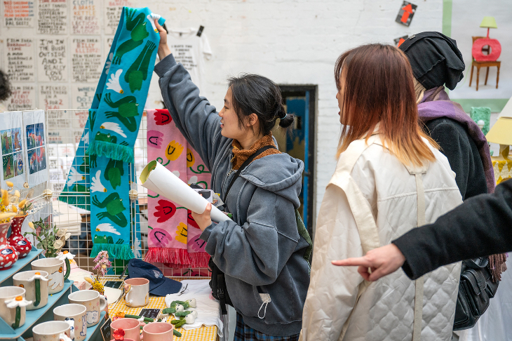 People browsing printed textiles at a stall at the DIY Art Market