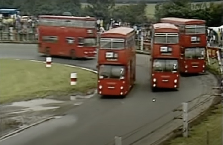 Four red double deckers on a tight race circuit