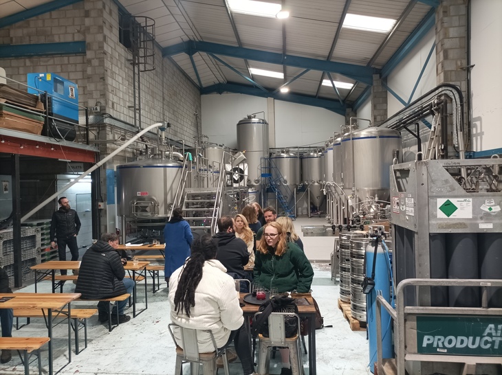 Brewery taprooms in London: People drinking in the brewery, with all the equipment behind.