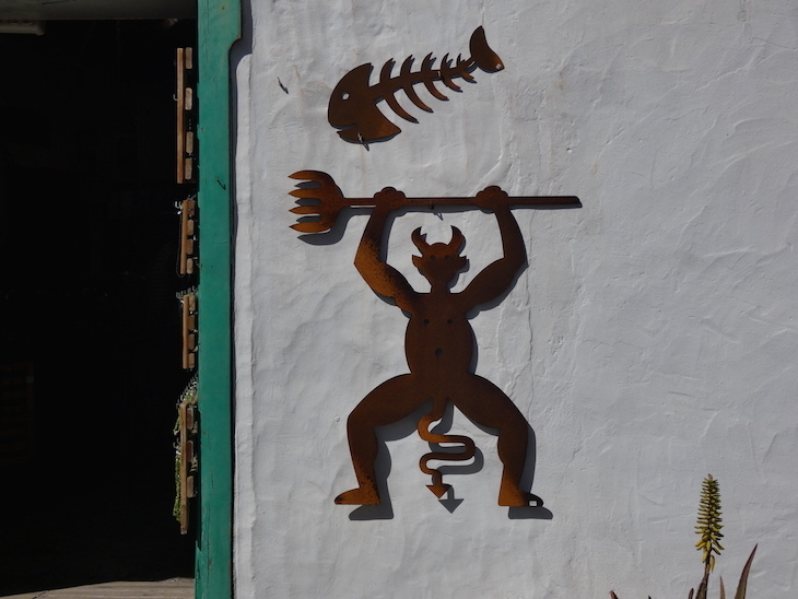 A silhouette of El Diablo on a whitewashed exterior wall.