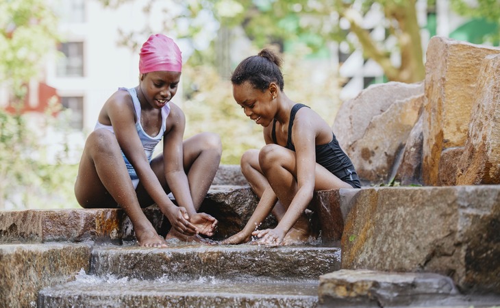 Two girls splash around in the fountains