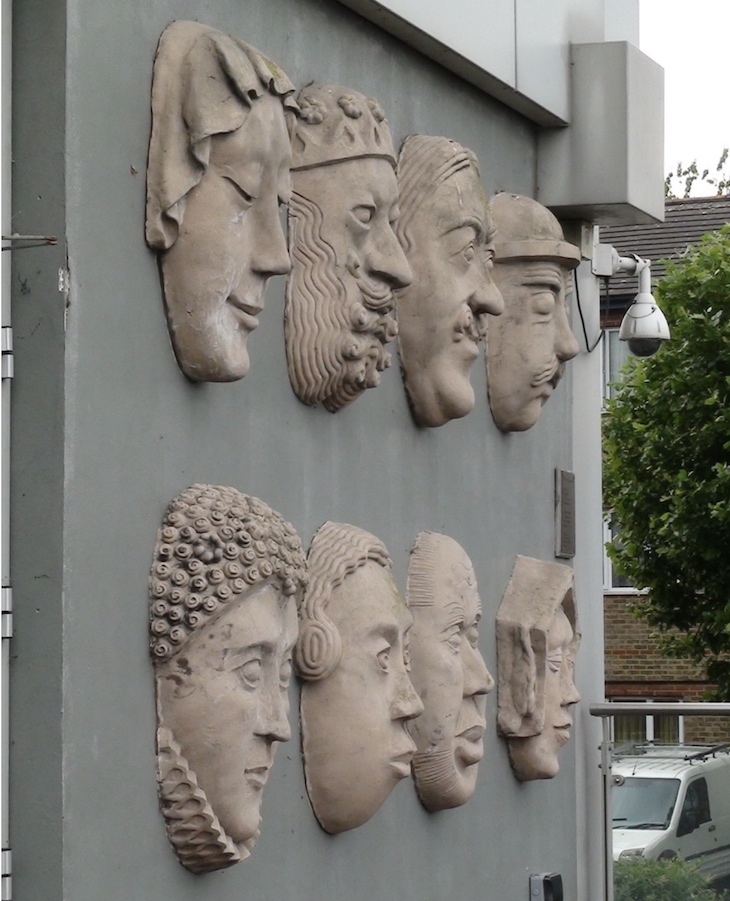 A wall of stone faces on a grey background