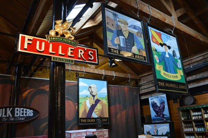 Brewery taprooms in London: Old Fuller's pub signs hanging from a beamed ceiling