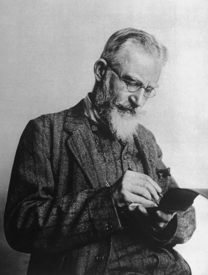 George Bernard Shaw with white beard, reading a book