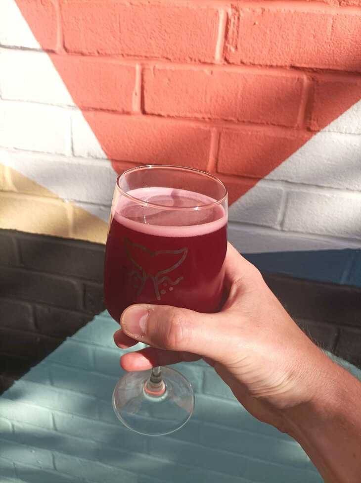 A deep red beer in front of a arty mural
