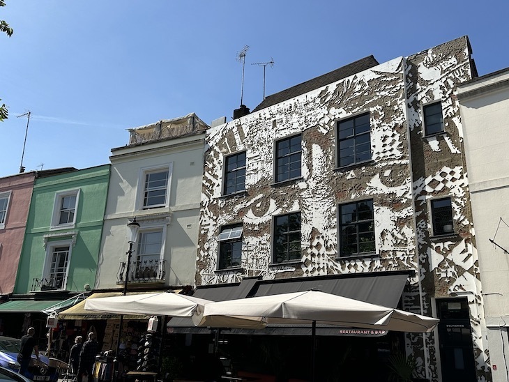 A three-storey facade whose white face has been chipped away to reveal a face