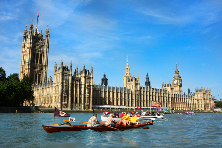 Boats being rowed down the Thames, past the Houses of Parliament.