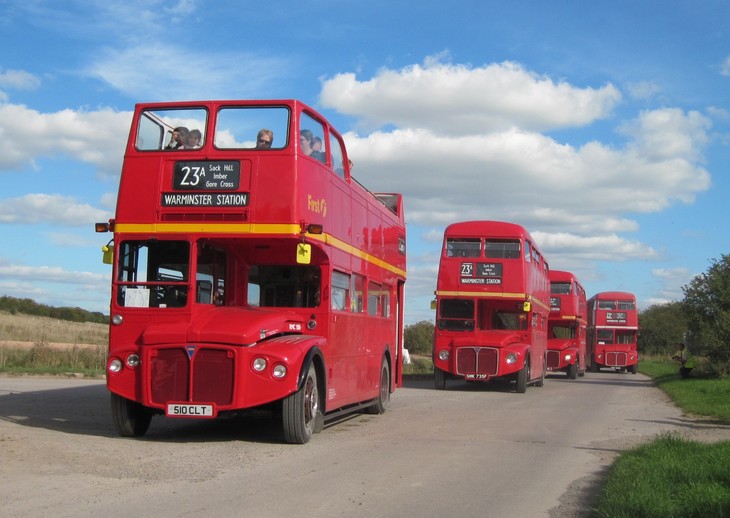 Imberbus 2023: a line of red double deckers driving down a country road