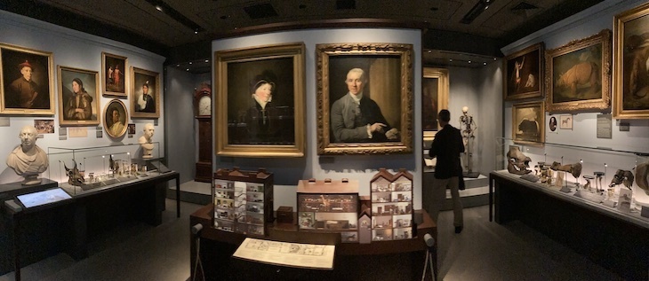 A museum room with portraits and specimens around the walls