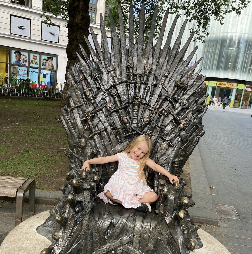 A young girl sits on a replica of the Iron Throne from Game of Thrones