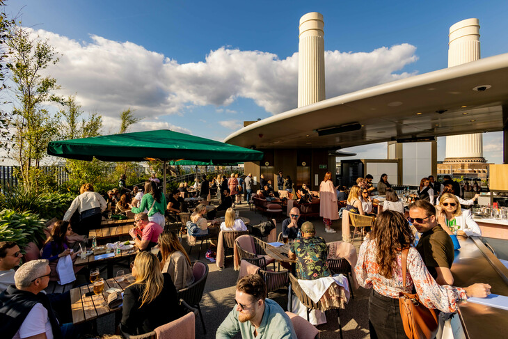 Best rooftop bars London: A busy roof terrace, with two of Battersea Power Stations white chimneys protruding in the background