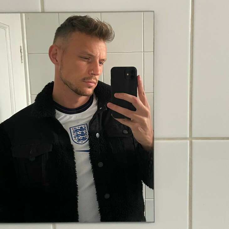 A young man in an England top taking a picture of himself in the mirror