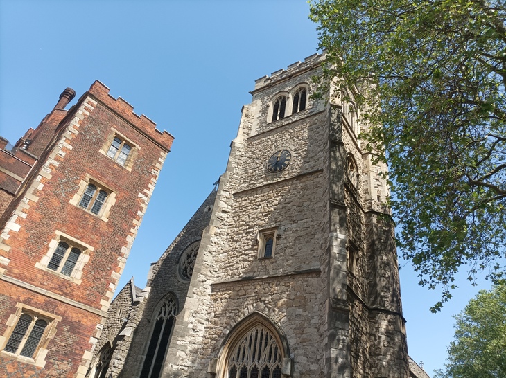 A redbrick palace tower next to an old grey church tower