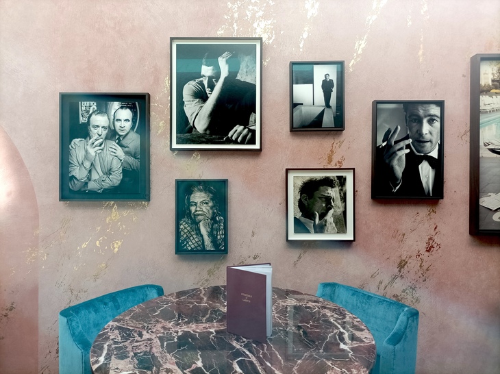 A pink marbled wall in a bar scattered with portraits of classic actors, in black and white