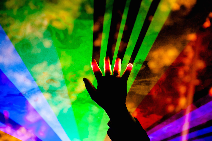 A hand reaches into a rainbow of club lights