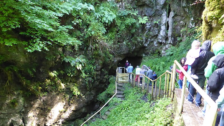 People descending down a staircase carved alongside a cliff into the caves.