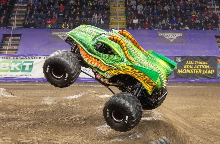 A bright green monster truck on its back wheels