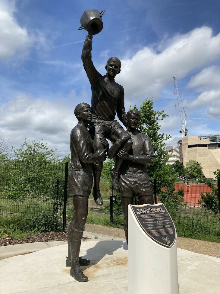 A trio of footballers in statue form lifting a cup