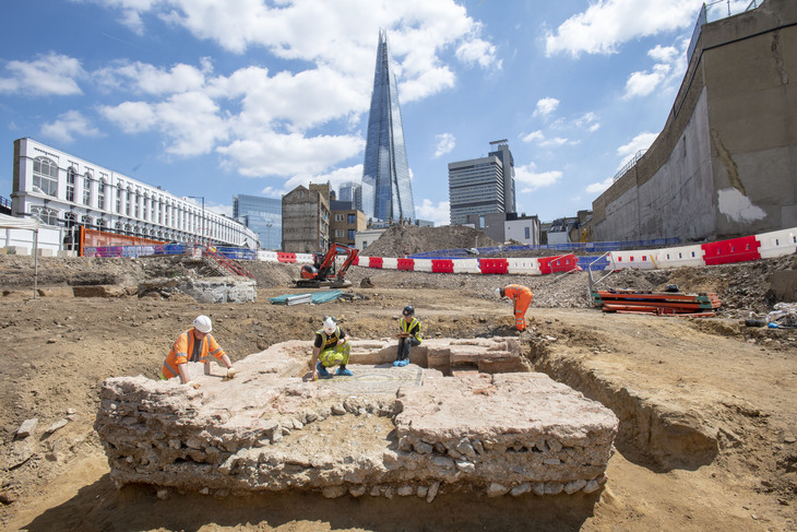 A team in high vis standing over the Roman remains, with the Shard rising in the background