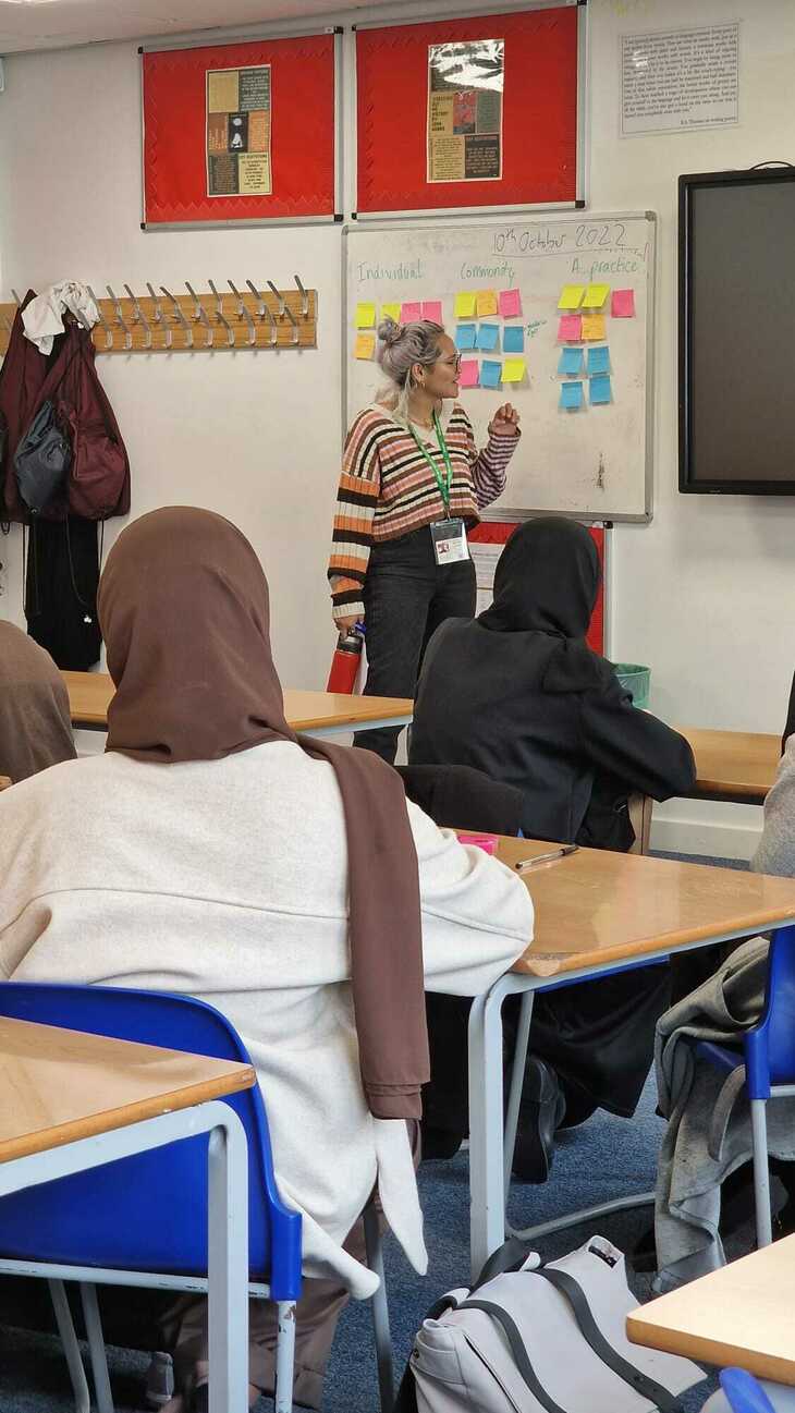Young women in hijabs face the front of a classroom