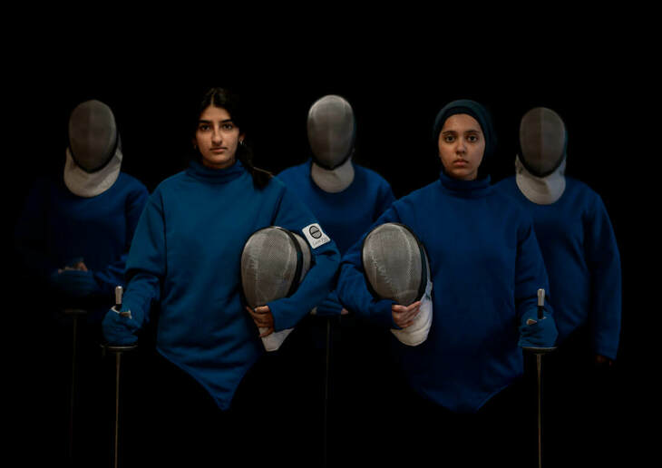 A group of fencers - two with their visors up - young women